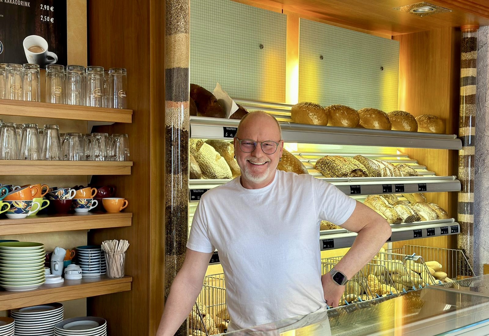 Kopie Bäckermeister Enrico Esche hinter der Ladentheke mit Brotsortiment im Hintergrund